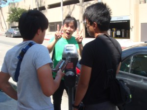 Normen gives the victory sign, as Cheng Yew and Jastine figure out the parking meter.